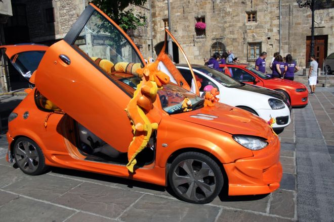 Coche naranja tuneado con las puertas abiertas y un equipo de sonido instalado
