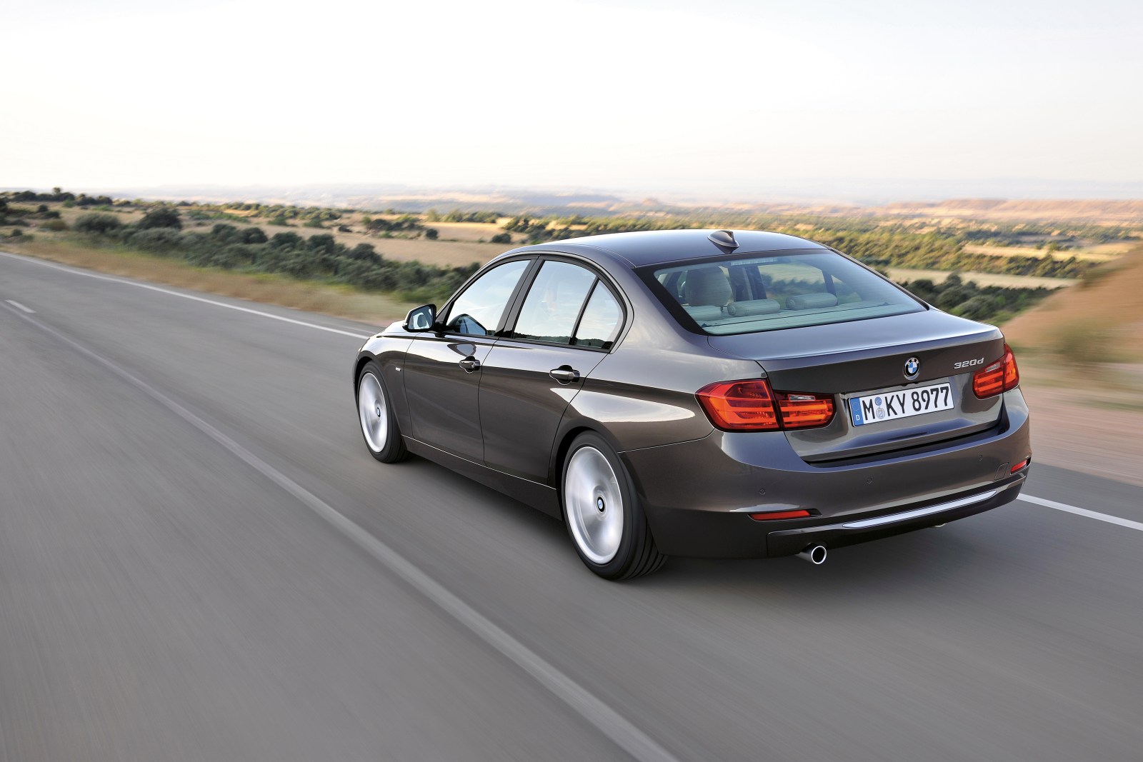 BMW Serie 3 F30 gris en movimiento por una carretera, vista trasera de tres cuartos
