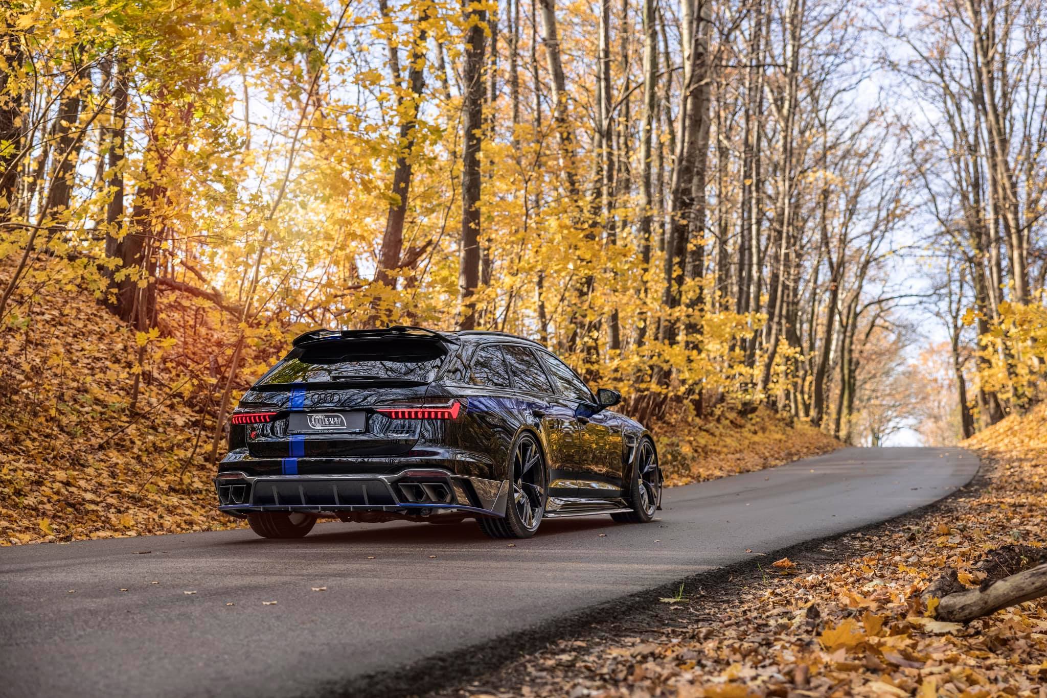 Audi RS6 Avant negro de MTM y Mansory visto desde atrás en una carretera arbolada en otoño.