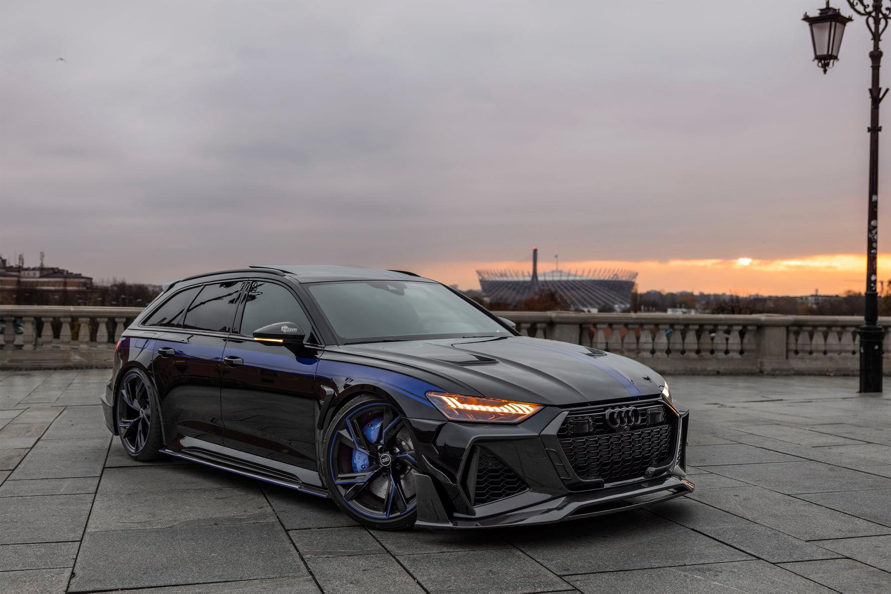 Audi RS6 Avant negro de MTM y Mansory en vista frontal de tres cuartos al atardecer.