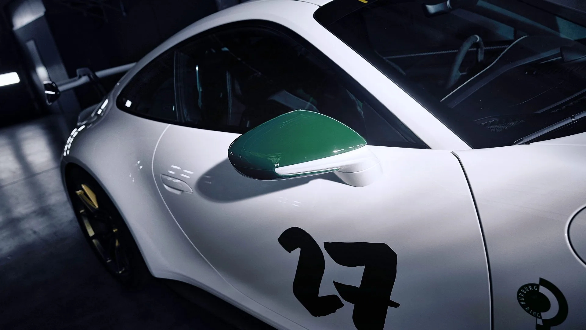 Detalle lateral del Porsche 911 GT3 100 Jahre con dorsal 77 y retrovisor verde